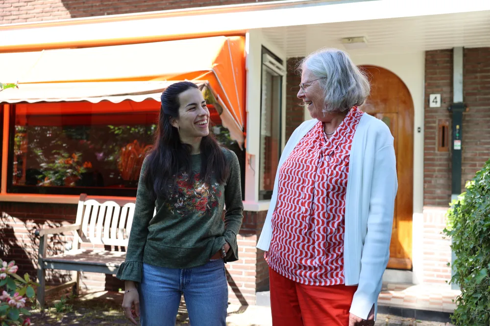 Een host en een potentiële huurder lopen pratend voor een huis