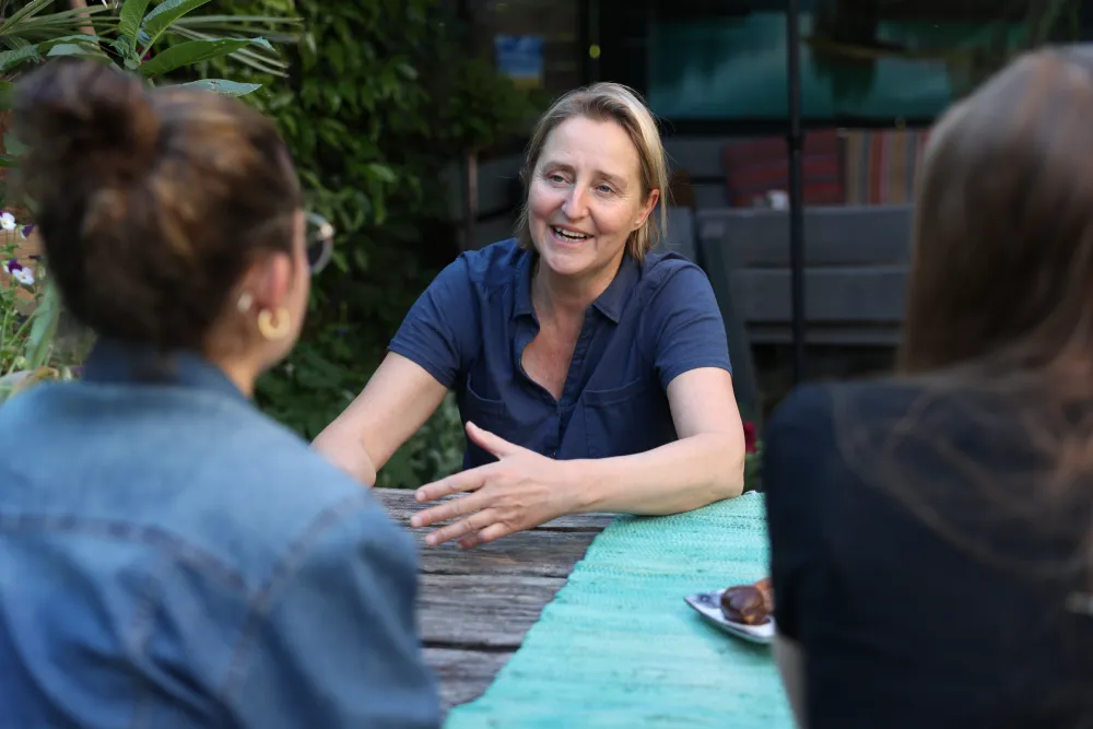 Een vrouw in gesprek met twee anderen aan een tuintafel