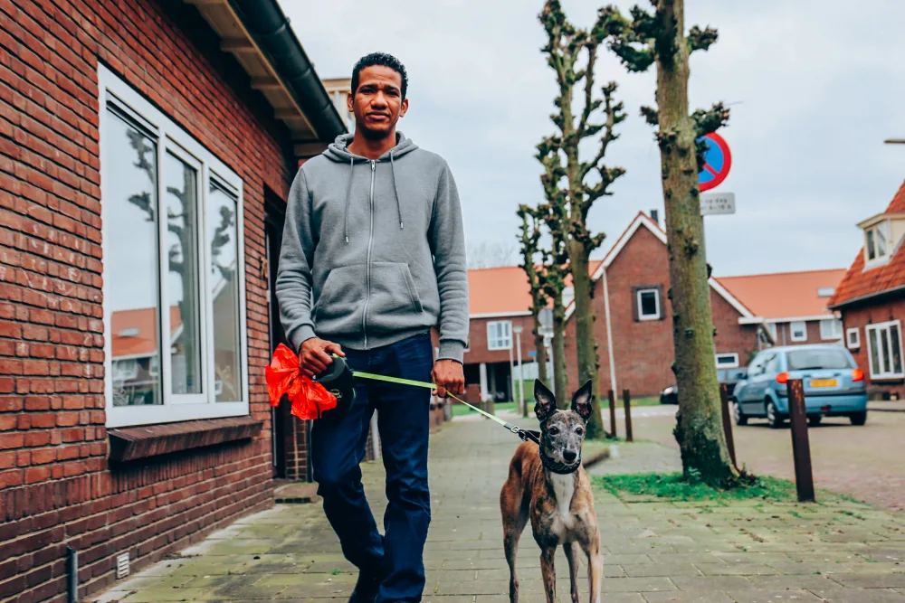 Een huurder laat de hond uit in de buurt