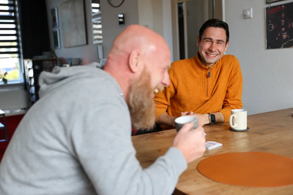 Twee mannen in gesprek aan tafel met koffie