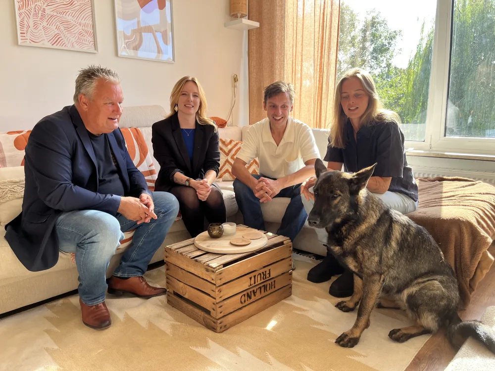 Vier mensen en een hond samen op de bank in de woonkamer