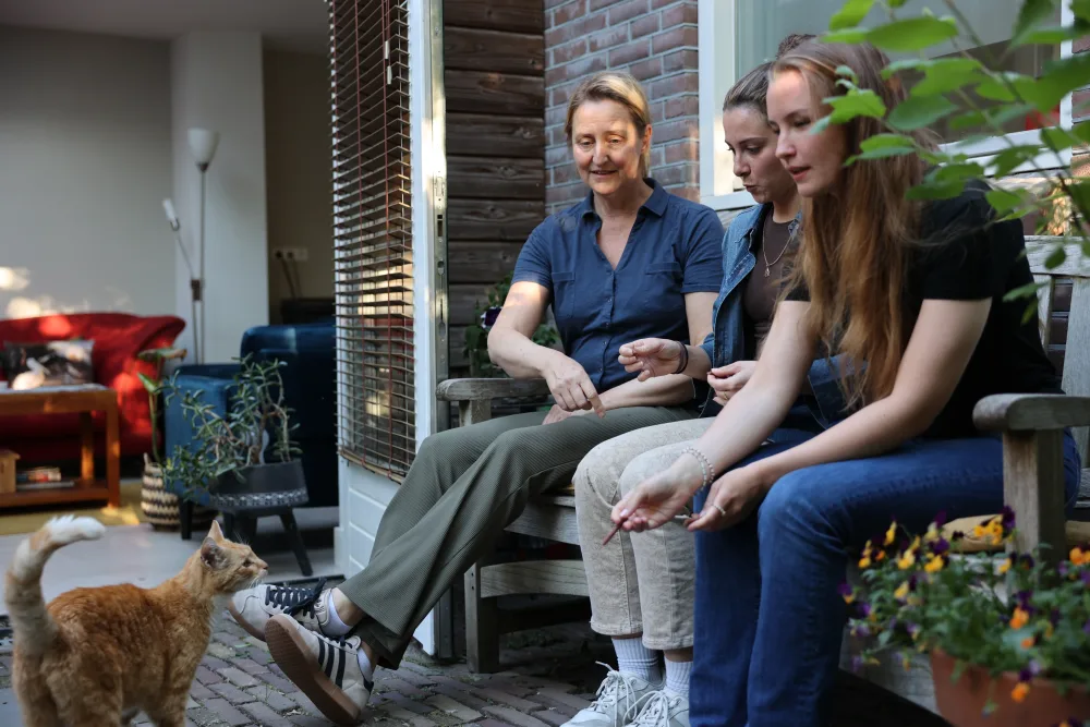 Een host in gesprek met twee huurders op een tuinbank, met een kat