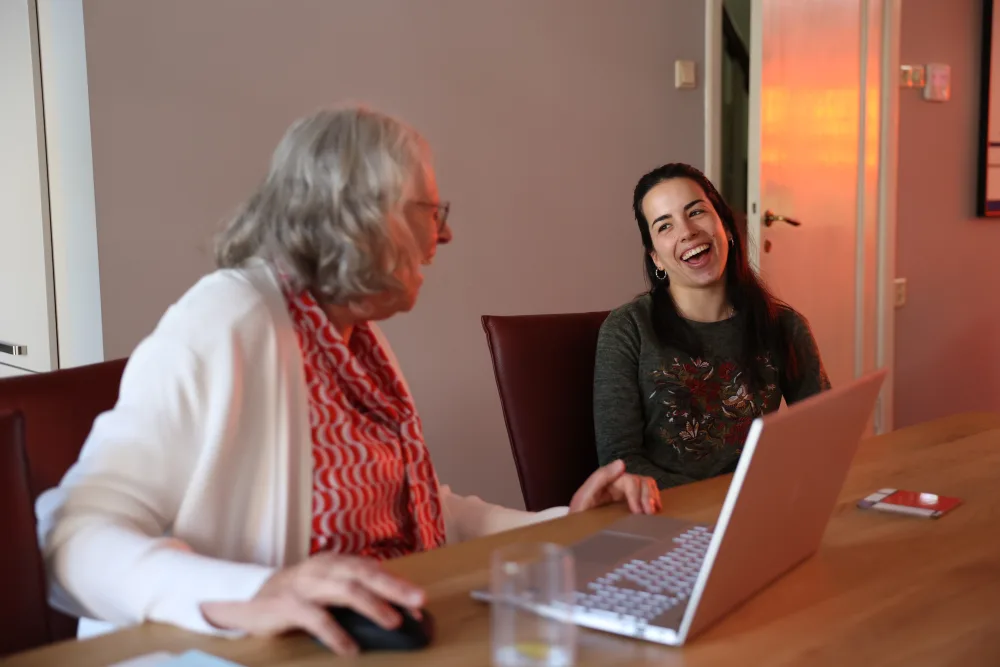 Een host en huurder lachen samen achter een laptop