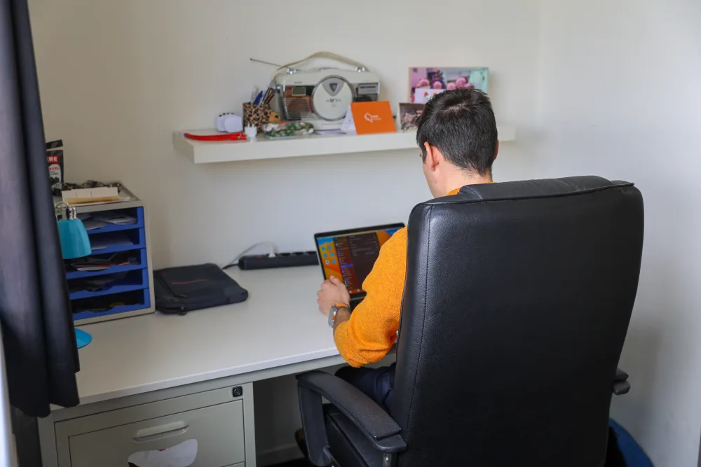 Een huurder werkt aan zijn bureau op zijn kamer