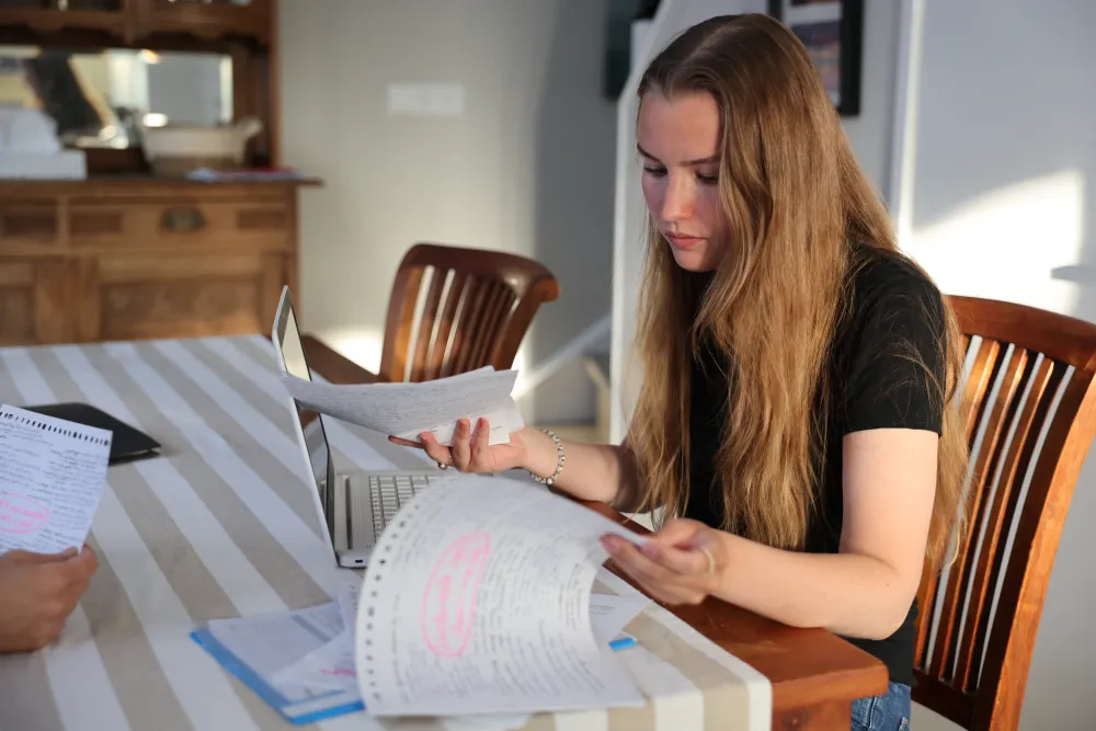 Een jonge vrouw bekijkt documenten aan de eettafel