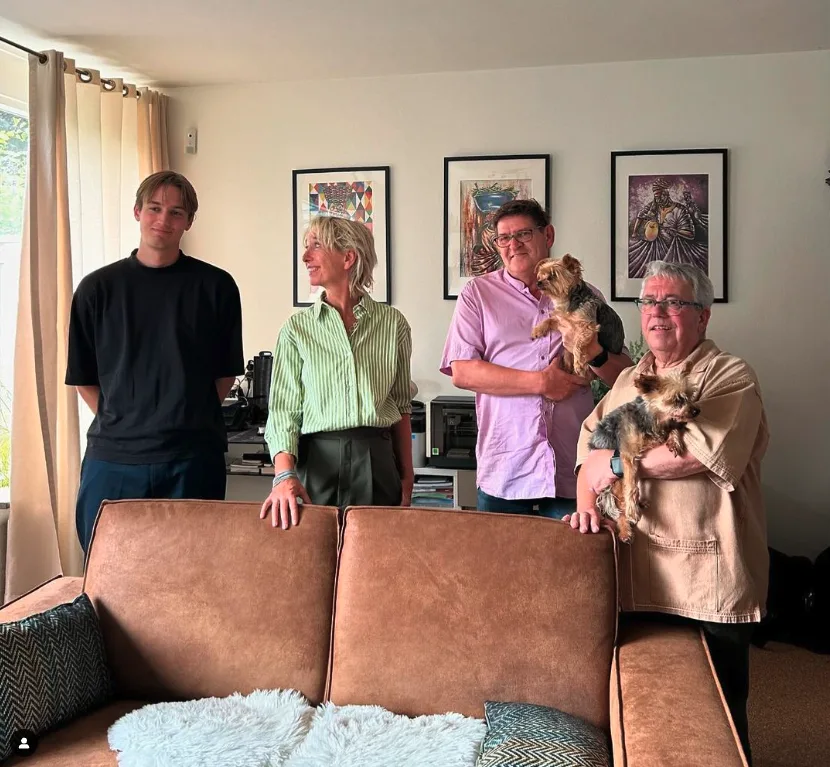 Een groep mensen in de woonkamer, één met een hondje